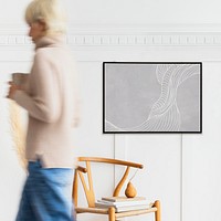 Woman walking past a black photo frame on a white wall mockup