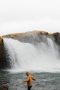 Man by the waterfall walking on rocks 