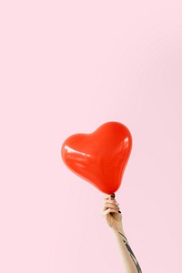 Tattooed arm holding a red heart shape balloon mockup