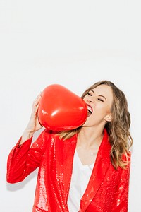 Woman in red jacket biting a red balloon