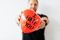 Man showing a heart red balloon with I Hate You text