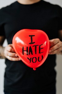 Man showing a heart red balloon with I Hate You wording 