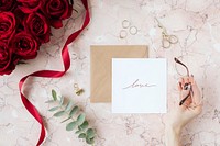 Woman holding eyeglasses over a table of roses and a card mockup