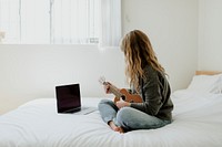 Woman using a laptop while playing ukulele during lockdown 