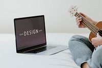 Woman using a laptop screen mockup while playing ukulele during quarantine 