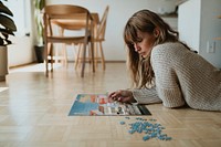 Woman assembling a jigsaw puzzle of Nyhavn, Copenhagen during coronavirus quarantine. 