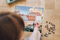 Woman assembling a jigsaw puzzle of Nyhavn, Copenhagen during coronavirus quarantine.