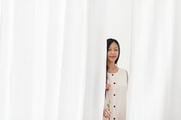 Asian woman with a dry pink peony flower in a hand walking through the white curtain