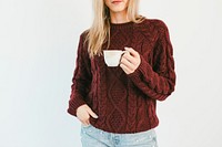 Blonde woman wearing a knitted sweater drinking warm tea 