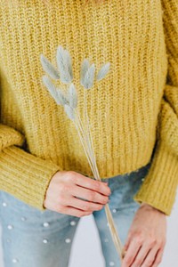 Woman in a yellow sweater holding a hare&#39;s tail grass 
