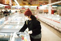 Woman with a medical mask buying frozen food during coronavirus pandemic