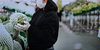 Woman with a medical mask buying fresh food during coronavirus pandemic