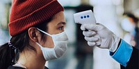 Woman in a medical mask getting her temperature measured by an electronic thermometer coronavirus banner 