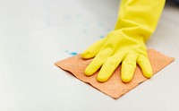 Rubber glove hand drying a wet floor to prevent the contamination