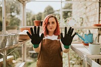 Woman gardener with black gloves in greenhouse