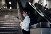 Asian girl checking social media on phone at the underground subway station