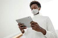 Man with face mask using digital tablet smart technology