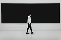 Man walking in front of a large billboard