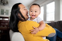 Cheerful Asian American father hugging his son