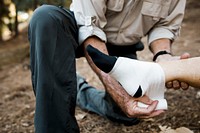 Elderly man bandaging his wife’s ankle 