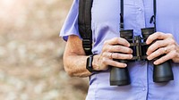 Senior woman with binoculars in the forest 