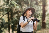 Active senior woman using binoculars to see the beauty of nature