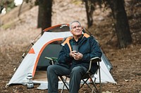 Chill senior man having coffee next to his tent 