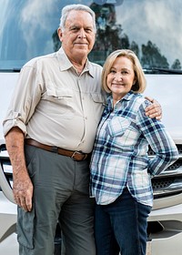 Happy senior couple standing in front of camper van