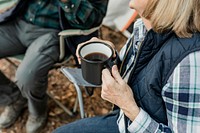 Happy retired couple having coffee by the tent in the forest 