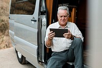Grandpa sitting in camper van while looking at his tablet
