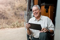 Grandpa sitting in camper van while looking at his tablet