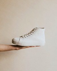 Hand holding white high top sneakers