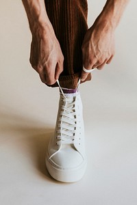 Man hands fixing shoelaces white high top shoes