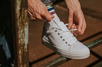 Man fixing shoelaces on white sneaker mockup