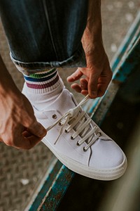 Man fixing shoelaces on white sneaker