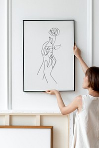 Woman arranging frame mockup psd on a wall in a Japandi decor room