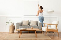 Woman arranging frame on a wall in a Scandinavian living room