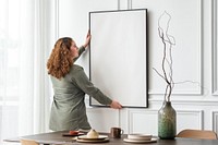 Woman hanging blank picture frame on the wall 