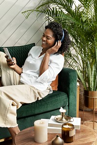 Cheerful woman listening to music through headphones at home