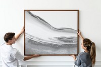 Frame mockup psd with abstract painting being hung by a couple