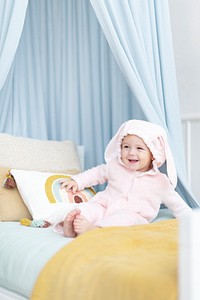 Cute baby girl sitting on her bed