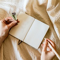 Open notebook psd mockup with flowers on linen blanket