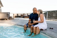 Couple having a drink by the pool while social distancing at home during covid-19