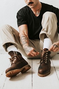 Alternative man tying boots shoelaces on the floor