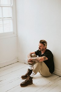 Alternative man sitting on a white wooden floor