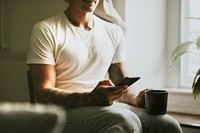 Urban tattooed man in white using digital mobile phone