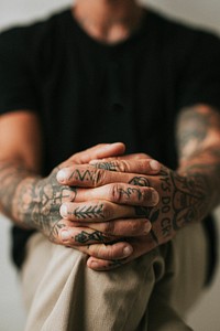 Tattooed man with hands clasping his knees. 2 OCTOBER 2020 - CHIPPENHAM, UK