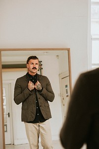 Fashionable man looking at himself in the mirror
