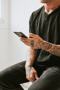 Alternative man in black tee using smartphone