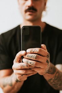Man with tattooed hands holding a phone. 2 OCTOBER 2020 - CHIPPENHAM, UK